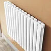 A white radiator is mounted on a brown wall, with a white skirting board at the bottom. Podgląd zdjęcia produktu