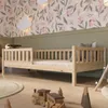 A child's bedroom with a wooden bed, toys, and floral wallpaper.
