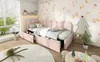 A child's bedroom with a pink upholstered bed, a small table and chairs, and decorative elements. Podgląd zdjęcia produktu