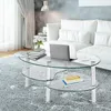 A modern living room with a glass coffee table in the foreground, a laptop, books, and a vase of flowers on it, and a white sofa in the background. Náhľad obrázku produktu