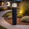 A modern black bollard light illuminates a garden path at dusk. Anteprima dell’immagine prodotto