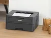 A Brother laser printer is shown on a wooden surface next to two decorative wooden candle holders. Produktbild-Vorschau