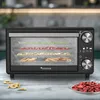 A TurboTronic food dehydrator is shown on a countertop, filled with dried fruits and vegetables. Some dried fruits are scattered on the surface in front of the appliance. Produktbild-Vorschau