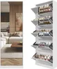 A white shoe cabinet with multiple shelves filled with shoes, placed next to a mirrored panel reflecting a living room scene. Produktbild-Vorschau