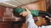 A person is using a green Bosch Delta sander to sand a wooden corner. Produktbild-Vorschau