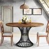 A round dining table with a metal base, set in a dining room with chairs, a door, and artwork on the wall. Podgląd zdjęcia produktu