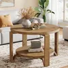 A living room scene featuring a round wooden coffee table with two shelves, decorated with a vase, books, and a small radio. Produktbild-Vorschau
