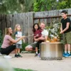 A family is roasting marshmallows over a Solo Stove Yukon fire pit in a backyard. Produktbild-Vorschau