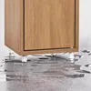 The bottom of a wooden cabinet is shown with its clear legs resting on a wet, grey floor. Náhled obrázku produktu