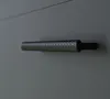 A close-up of a textured metal handle on a gray surface. Náhled obrázku produktu
