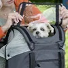 A woman is holding a dog carrier with a small dog inside. Produktbild-Vorschau