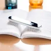 A silver pen-like device rests on an open book. Náhľad obrázku produktu