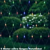 A net of colorful lights is hung in front of bushes and trees in a garden setting. Voir les images du produit