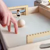A child's hand is playing with a wooden table football game. Produktbild-Vorschau