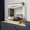 A lighted mirror is placed on a dresser in a bedroom, reflecting a bed. Anteprima dell’immagine prodotto