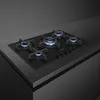 A modern gas stovetop with five burners, all lit with blue flames, sits on a dark countertop. Anteprima dell’immagine prodotto
