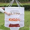 A person is shown placing food items into a hanging drying net outdoors. Produktbild-Vorschau