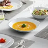 A table setting with plates of food, soup, and salad. Produktbild-Vorschau