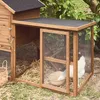 A wooden chicken coop with a wire mesh enclosure, set in a grassy outdoor area with foliage in the background. Produktbild-Vorschau