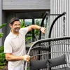 A man stands next to a hanging chair in an outdoor setting. Produktbild-Vorschau