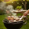 A person is grilling burgers and vegetable skewers on a BBQ grill in a backyard setting. Náhled obrázku produktu