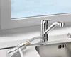 A chrome kitchen faucet with a flexible hose attached, positioned over a stainless steel sink, with a window in the background. Produktbild-Vorschau
