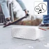 A white Bluetooth speaker is placed on a gray surface, with a person skateboarding in the blurred background. A circular icon with a clock and musical note indicates 10 hours of battery life. Anteprima dell’immagine prodotto