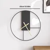 A modern wall clock with a minimalist design is shown mounted on a white wall. Produktbild-Vorschau