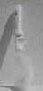 A white toilet brush with a liquid dispenser attached, leaning against a textured white wall. Produktbild-Vorschau