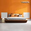 A bedroom scene with a bed, pillows, and two white panels on an orange wall. A logo is visible in the top right corner. Anteprima dell’immagine prodotto