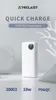 A white power bank is displayed on a white surface with decorative elements in the background. Náhled obrázku produktu