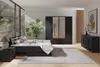 A modern bedroom with a black bed, wardrobe, and dresser, decorated with plants and artwork. Produktbild-Vorschau