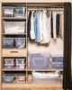 A closet with storage boxes and clothes hanging on a rack. Anteprima dell’immagine prodotto
