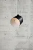 A black and white pendant light hangs against a concrete wall. Voir les images du produit