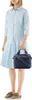 A woman is standing and holding a handbag. Anteprima dell’immagine prodotto