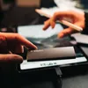 A person is holding a Verbatim external SSD while another person uses a stylus on a tablet in the background. Anteprima dell’immagine prodotto