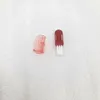 A close-up shot of a small red toothbrush and its pink cap on a white textured background. Náhled obrázku produktu