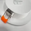 A close-up view of a white LED downlight with an orange clip and a metal spring. Anteprima dell’immagine prodotto