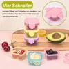A collection of small, colorful food storage containers filled with various fruits and vegetables, arranged on a wooden cutting board and a pink surface. Produktbild-Vorschau