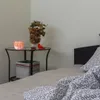 A bedside table with a salt lamp and a vase of dried flowers next to a bed. Anteprima dell’immagine prodotto