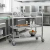 A stainless steel serving trolley with three shelves in a commercial kitchen setting. Voir les images du produit