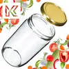 A clear glass jar with a gold lid is shown tilted on a white background, surrounded by various fresh vegetables and herbs. Náhled obrázku produktu