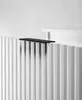A close-up shot of a black shelf placed on top of a white ribbed radiator or cabinet. Produktbild-Vorschau