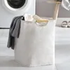 A laundry basket filled with clothes next to a washing machine. Produktbild-Vorschau