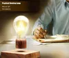 A person is writing in a notebook next to a levitating light bulb lamp. Produktbild-Vorschau