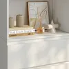 A close-up view of a white shelf with decorative items and books. Produktbild-Vorschau