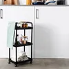 A three-tiered black rolling cart filled with kitchen items and towels, placed against a white cabinet background. Anteprima dell’immagine prodotto