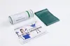 A green TheraBand exercise band, its cylindrical packaging, and an instruction booklet are arranged on a white surface. Produktbild-Vorschau