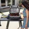 A woman is grilling steaks and asparagus on an outdoor electric grill. Voir les images du produit