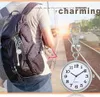 A person wearing a backpack with a fob watch attached to it, standing near train tracks. Produktbild-Vorschau